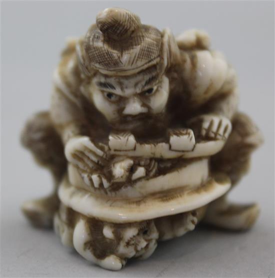 A Japanese walrus ivory netsuke of Shoki crushing two oni, signed Gyokuzan, Meiji period, 3.8cm